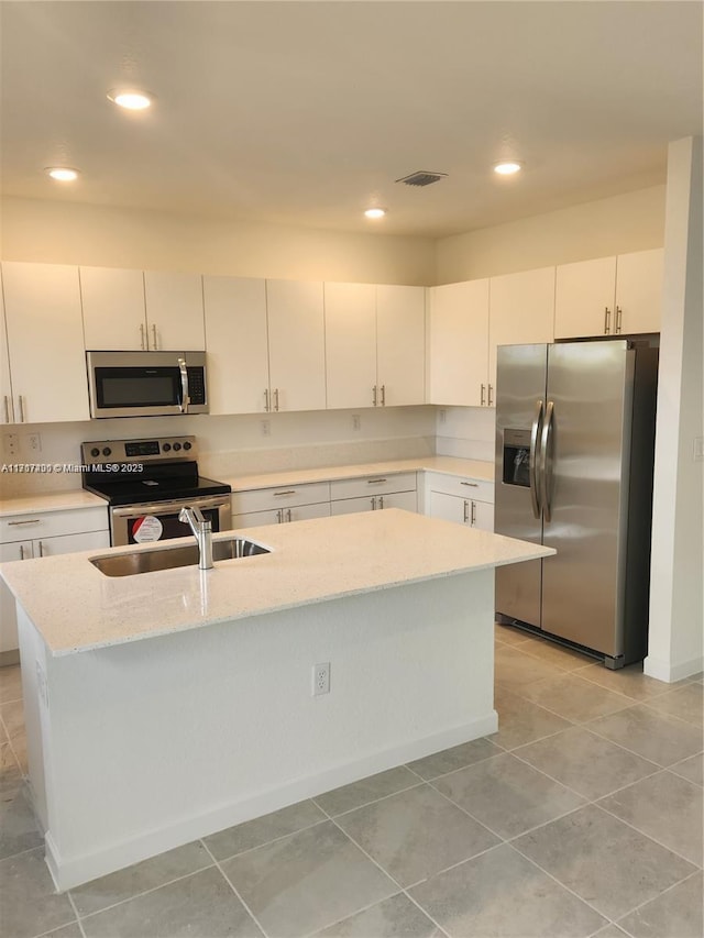 kitchen with white cabinets, appliances with stainless steel finishes, sink, and an island with sink