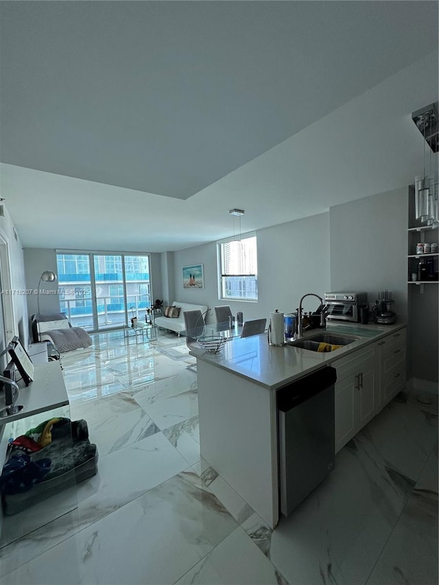 kitchen with kitchen peninsula, white cabinets, sink, dishwasher, and hanging light fixtures