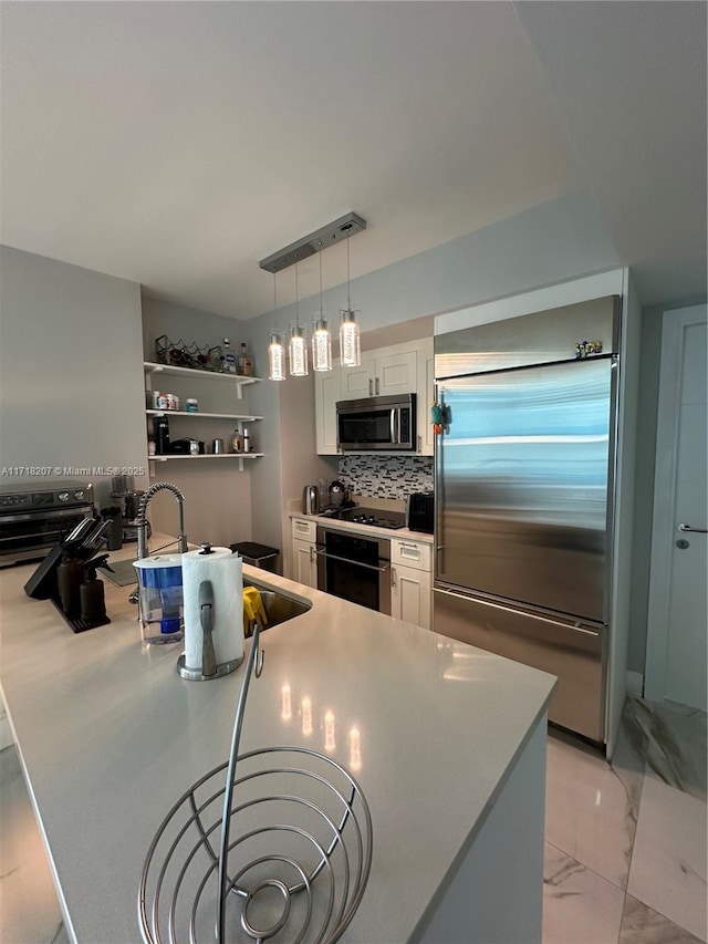 kitchen with appliances with stainless steel finishes, backsplash, decorative light fixtures, and white cabinetry