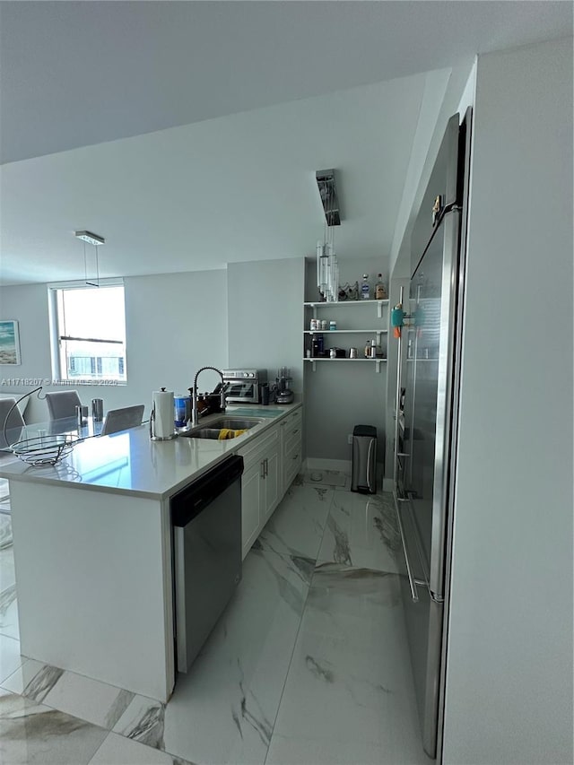 kitchen with kitchen peninsula, stainless steel appliances, sink, white cabinetry, and hanging light fixtures