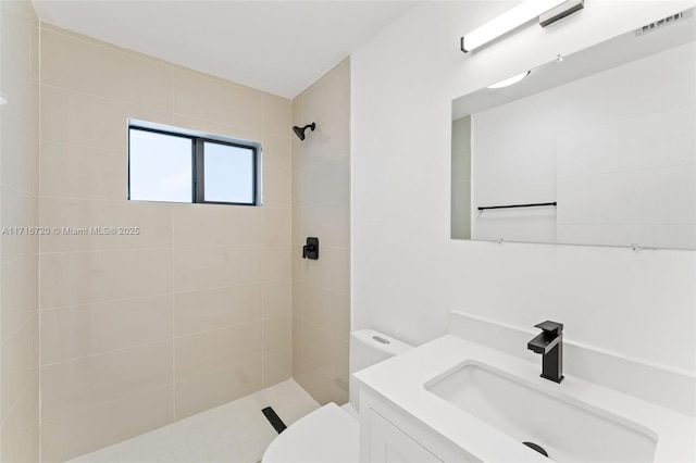 bathroom with vanity, toilet, and tiled shower