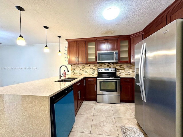 kitchen featuring kitchen peninsula, backsplash, stainless steel appliances, sink, and decorative light fixtures