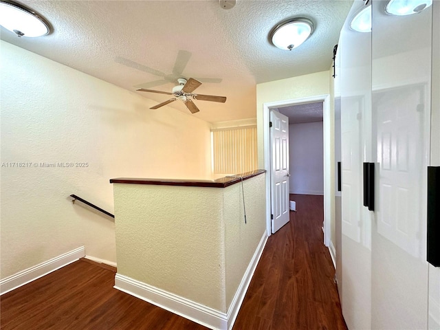 corridor featuring a textured ceiling and dark wood-type flooring