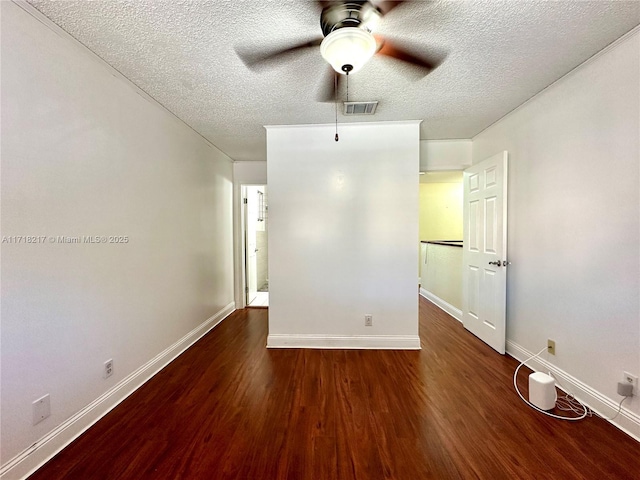 empty room with a textured ceiling, ceiling fan, and dark hardwood / wood-style floors