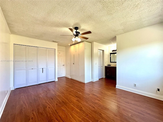 unfurnished bedroom featuring a textured ceiling, dark hardwood / wood-style floors, ensuite bath, and ceiling fan