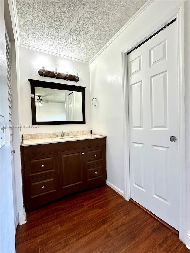 bathroom featuring hardwood / wood-style flooring, vanity, crown molding, and a textured ceiling