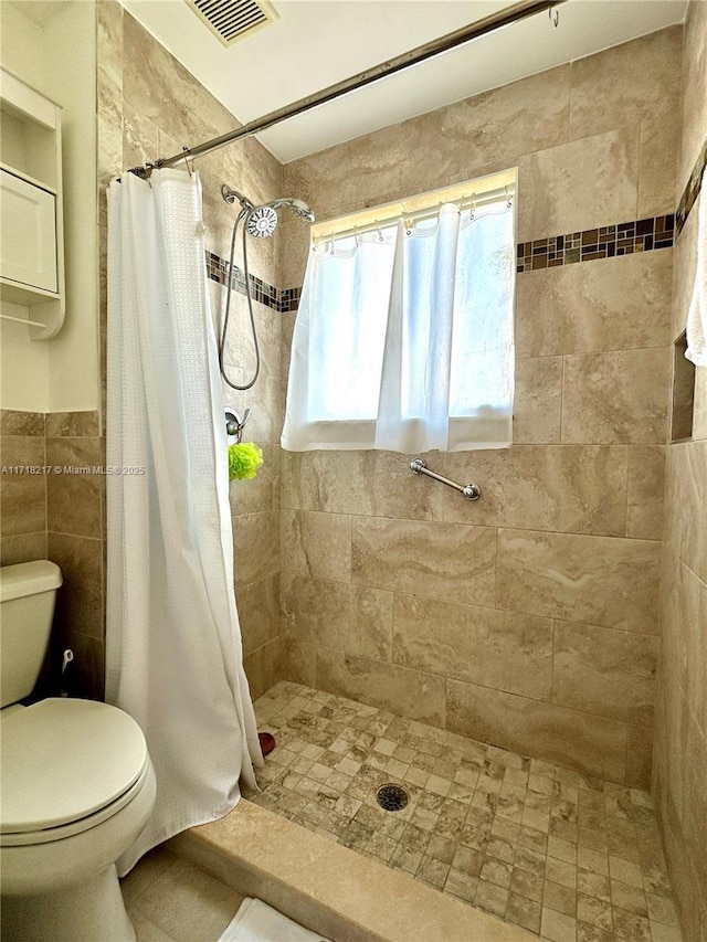 bathroom with toilet, tile walls, and a shower with shower curtain