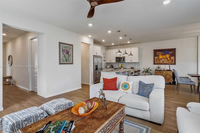 living room with light hardwood / wood-style floors and ceiling fan