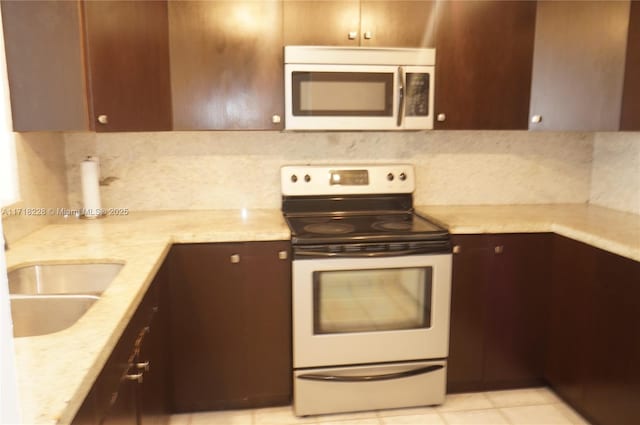 kitchen featuring white electric range, tasteful backsplash, light stone counters, dark brown cabinets, and light tile patterned floors