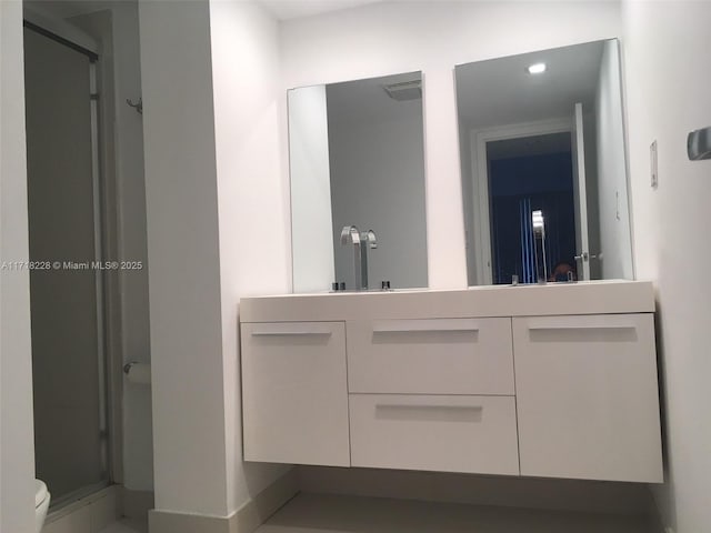 bathroom with toilet, vanity, and walk in shower