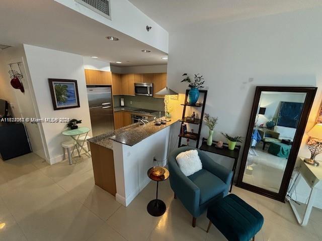 kitchen featuring dark stone countertops, appliances with stainless steel finishes, kitchen peninsula, and light tile patterned floors