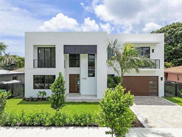 contemporary house featuring a balcony, a front lawn, and a garage