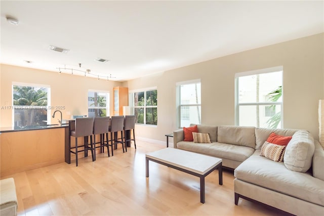 living room with light wood-type flooring, sink, and a wealth of natural light