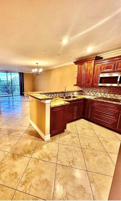 kitchen with sink, hanging light fixtures, black electric cooktop, kitchen peninsula, and a chandelier