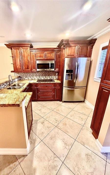 kitchen with crown molding, sink, light stone counters, kitchen peninsula, and stainless steel appliances