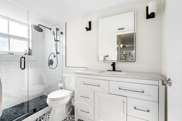 bathroom with a wealth of natural light, a shower with door, vanity, and toilet