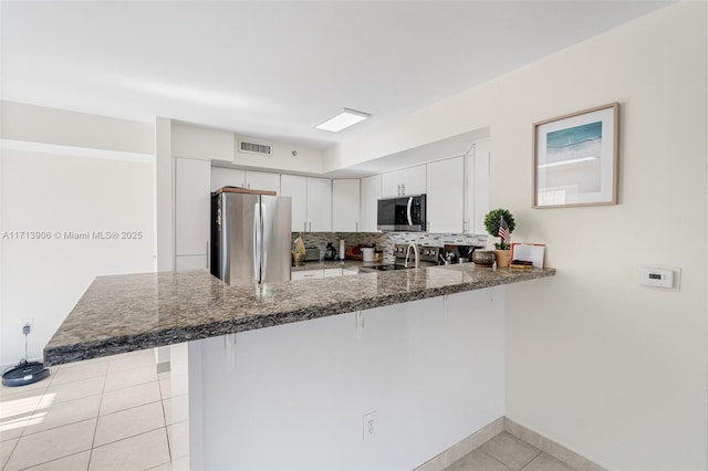 kitchen featuring white cabinets, light tile patterned floors, kitchen peninsula, and appliances with stainless steel finishes