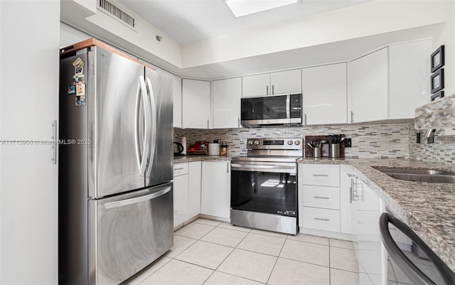 kitchen with tasteful backsplash, white cabinetry, sink, and stainless steel appliances