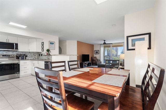 tiled dining room with ceiling fan and sink