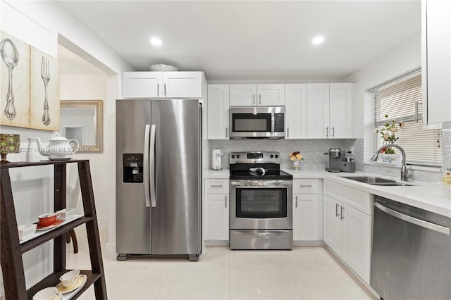 kitchen featuring backsplash, sink, white cabinets, and appliances with stainless steel finishes