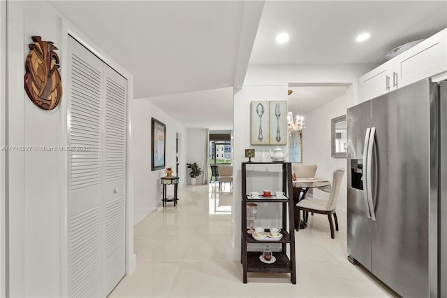 kitchen with white cabinets, stainless steel fridge with ice dispenser, pendant lighting, and a notable chandelier