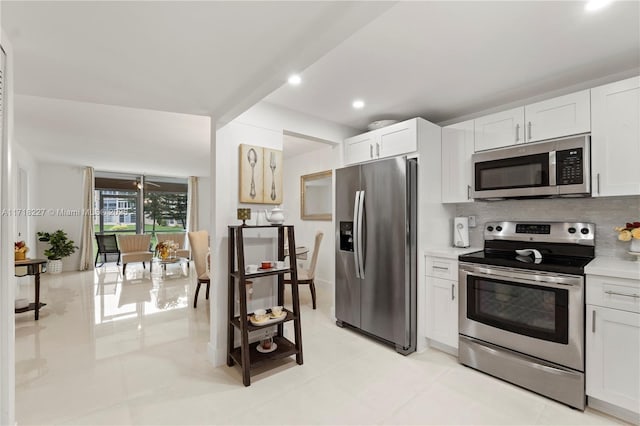 kitchen featuring white cabinetry, stainless steel appliances, light tile patterned floors, and tasteful backsplash