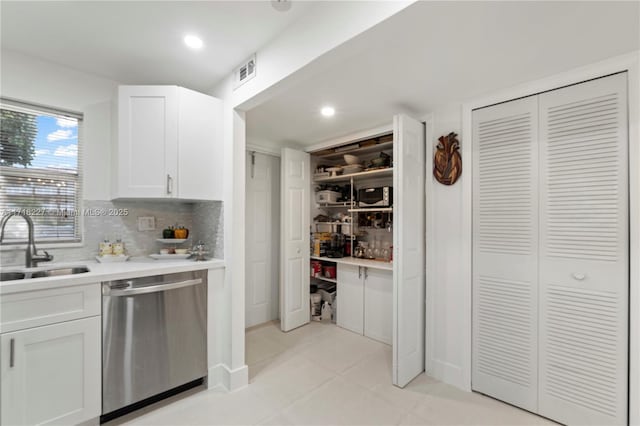 kitchen featuring dishwasher, sink, light tile patterned floors, tasteful backsplash, and white cabinetry