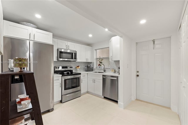 kitchen with white cabinets, decorative backsplash, sink, and stainless steel appliances