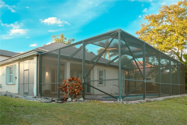 view of side of property with a lawn and glass enclosure