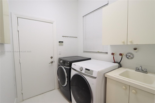 clothes washing area with cabinets, washer and dryer, and sink