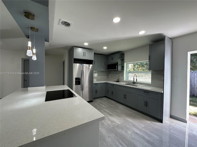 kitchen featuring decorative backsplash, appliances with stainless steel finishes, sink, gray cabinets, and hanging light fixtures