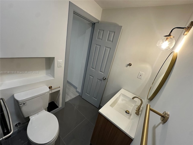 bathroom with toilet, vanity, and tile patterned floors