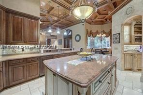 kitchen featuring tasteful backsplash, coffered ceiling, stone tile flooring, and a kitchen island