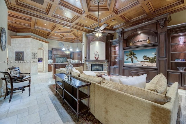 living room featuring stone tile floors, a ceiling fan, coffered ceiling, ornamental molding, and a glass covered fireplace