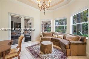 living room featuring a raised ceiling, a notable chandelier, and ornamental molding