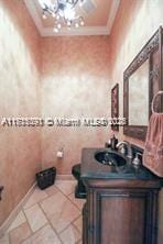 bathroom with vanity, crown molding, a notable chandelier, and tile patterned flooring