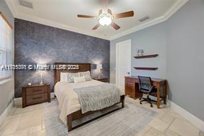 bedroom with visible vents, ornamental molding, wallpapered walls, baseboards, and an accent wall