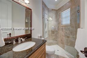 full bathroom with a shower stall, toilet, vanity, and ornamental molding