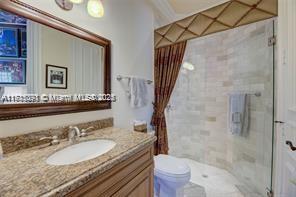 full bathroom featuring vanity, a shower stall, toilet, and ornamental molding