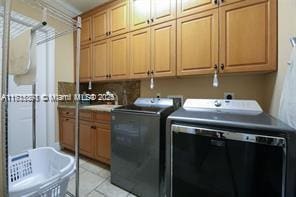 laundry area featuring light tile patterned floors, cabinet space, washer and dryer, and a sink