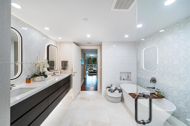 bathroom with vanity, tile walls, and a bathing tub