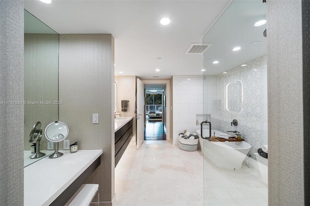 bathroom featuring tile patterned floors, vanity, a bath, and tile walls