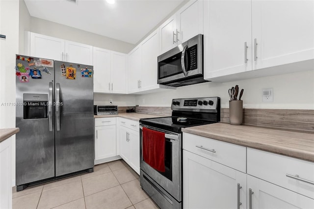 kitchen featuring light tile patterned flooring, white cabinetry, and stainless steel appliances