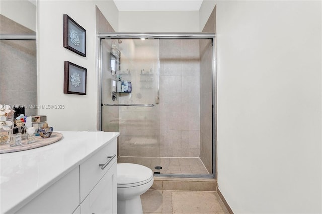 bathroom featuring vanity, a shower with shower door, and toilet