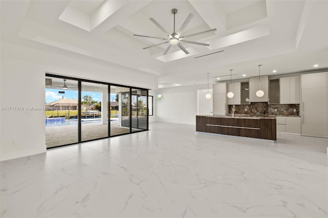 unfurnished living room featuring coffered ceiling, ceiling fan, a high ceiling, and beam ceiling