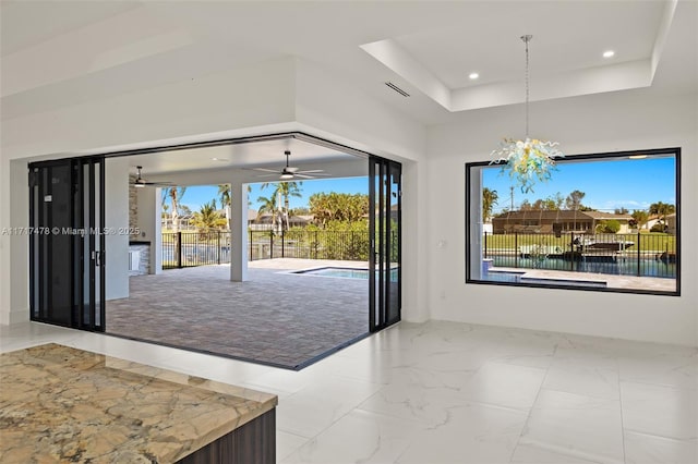 dining space featuring ceiling fan with notable chandelier, a tray ceiling, and plenty of natural light