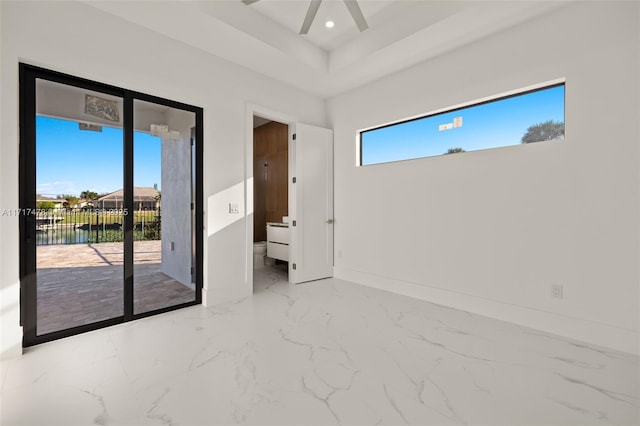 unfurnished bedroom featuring access to exterior, ceiling fan, and a raised ceiling