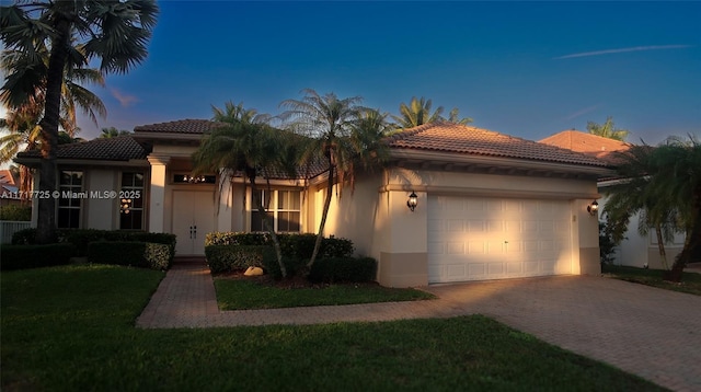 mediterranean / spanish-style home featuring a yard and a garage