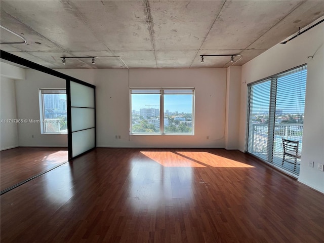 unfurnished room with hardwood / wood-style floors, a wealth of natural light, and track lighting