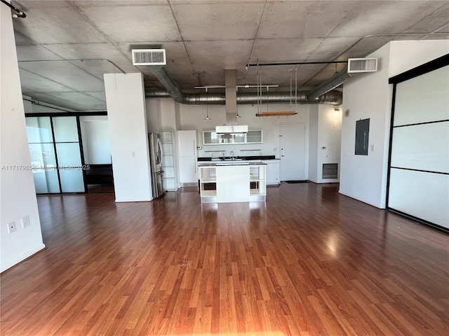 unfurnished living room featuring dark hardwood / wood-style flooring, electric panel, sink, and a high ceiling